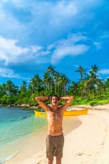 Young man enjoying summer vacations on a stunning beach in kawhagan island, philippines, surrounded