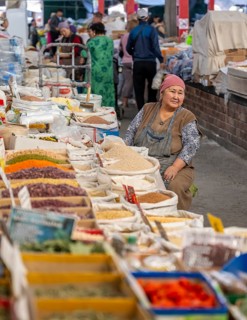 Traditional woman selling spices, flour and food, market stall at Osh Bazaar, Bishkek, Kyrgyzstan