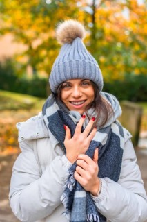 Vertical portrait of a beauty woman smiling at camera wearing warm clothes and woolly hat standing