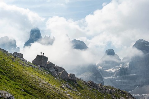 Alpine panorama, mountaineers on a large rock, fog and Torre Di Brentai and Cima Tosa, rocky