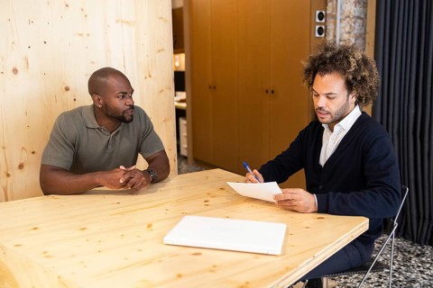 Two men engage in a focused meeting in a coworking space in Barcelona, seated at a modern wooden