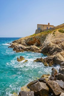 Small house in Koromacna Bay built on the rocks above the sea with a view of the sea on a sunny day