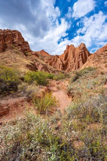 Eroded mountain landscape with sandstone cliffs, canyon with red and orange rock formations,