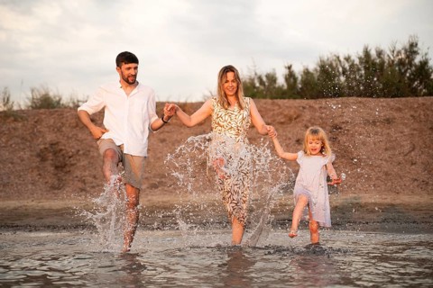 A joyful family splashes in shallow beach waters in Italy, enjoying quality time and creating