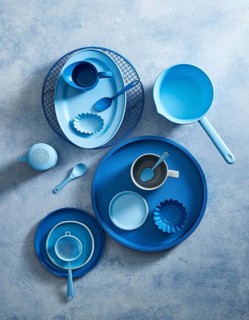 Top view of a stylish blue ceramic crockery set arranged on a textured gray background. The set