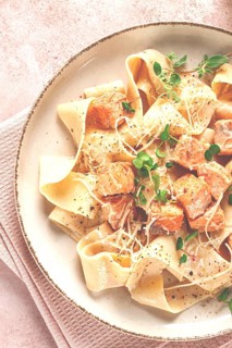 Tagliatelli pasta, with salmon slices and herbs, on a decorative plate, homemade, no people