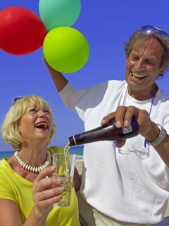 Seniors, couple on the beach in Ibiza, balloons, champagne, celebration, holiday joys