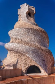 Whimsical chimney covered in colorful mosaic tiles stands out against a vibrant blue sky,