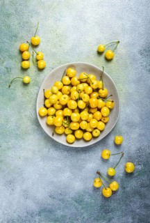 Yellow cherry, cherry berry, scattered on a plate, top view, no people
