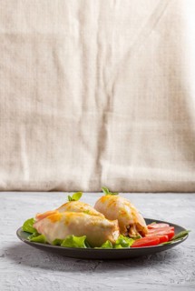 Stuffed baked squid with greens on a blue ceramic plate on a gray concrete background, side view,