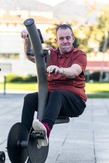 A man with an intellectual disability engages in physical activity on outdoor fitness equipment.