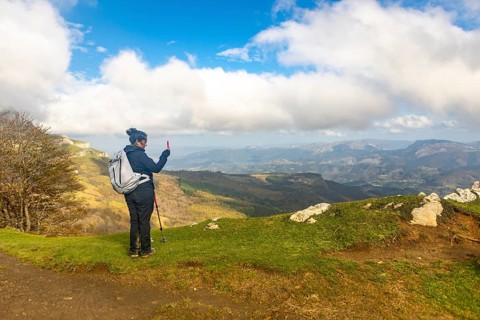 A woman hikes through the picturesque autumn landscape of Gorbea Natural Park in the Basque