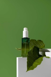 A striking image of a green essential oil bottle, adorned with a leaf, positioned on a white stand