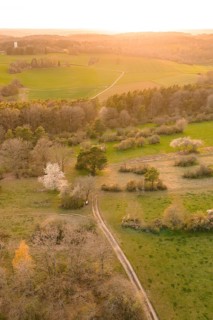 Rural trail through green fields in an illuminated evening landscape, e-bike tour, old sports field