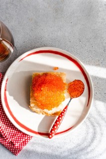 Top view of a vibrant, enticing plate of organic red caviar from trout, served on toast with a red