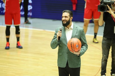 Syrian President Ahmad Al-Sharaa holds a basketball on the court during the official reopening