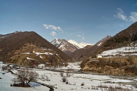 Captivating landscape of Caucasus snow covered mountains and valleys under a clear blue sky in a