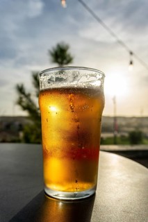Cold glass of beer with condensation and bubbles, reflecting the warm golden hour light on an