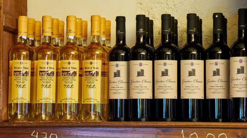 A rack with various wine bottles, yellow and black labels visible, Achaia Clauss winery, Patras,