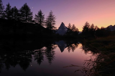 A breathtaking view of the Matterhorn at dawn, captured in the Swiss Alps. Reflecting in a tranquil