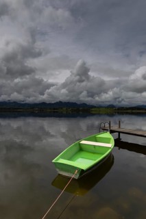 Storm clouds at sunset, a green rowing boat lashed to the wooden jetty, Hopfensee, Hopfen am See,