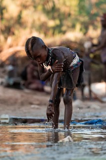 Himba child washing with water on a river, traditional Himba, Kaokoveld, Kunene, Namibia
