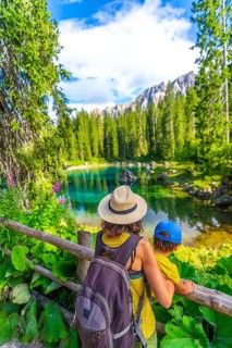 Tourists enjoying breathtaking view of lake carezza surrounded by dolomites mountains in summer