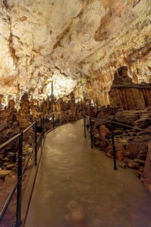 Tourists walking along a footpath, discovering stunning stalactites and stalagmites inside postojna