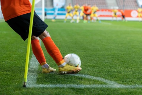 Footballer takes the corner. Detail of player's legs and the ball during soccer match in Lubin,