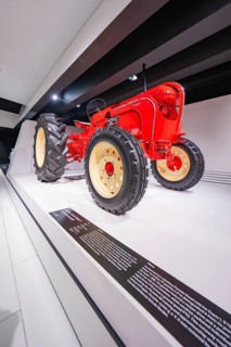 Retro-style tractor with large tires, in focus in an exhibition, Porsche Museum, Stuttgart, Germany