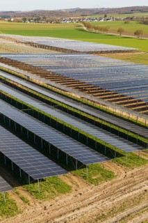 Landscape with solar fields, nearby villages visible in the background, Agri PV Bau für