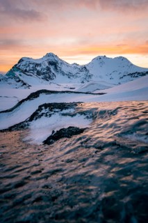 A stunning winter sunset illuminates the snowy ridges and frozen textures of Katla Glacier in