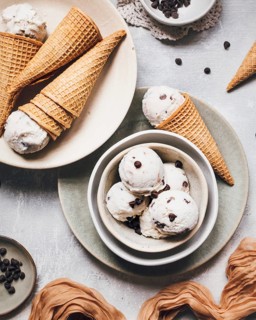Delicious banana ice cream scoops with chocolate chips are served in crispy waffle cones.