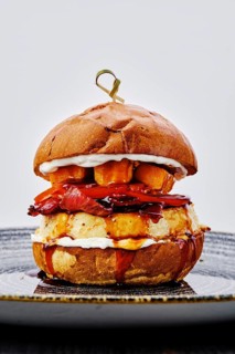 Close up view of burger with beef, bacon, pumpkin and tomato