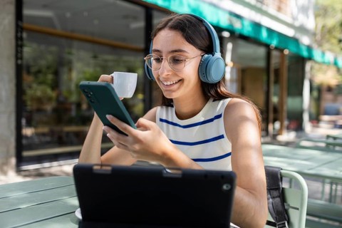 A woman enjoying an outdoor urban lifestyle, sipping coffee while engaging with her smartphone and
