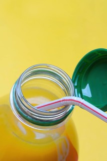Orange juice in plastic bottle with cap and straw