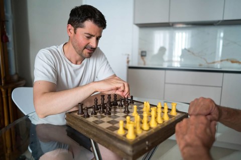 Cropped unrecognizable father and adult son enjoy a game of chess, fostering intergenerational