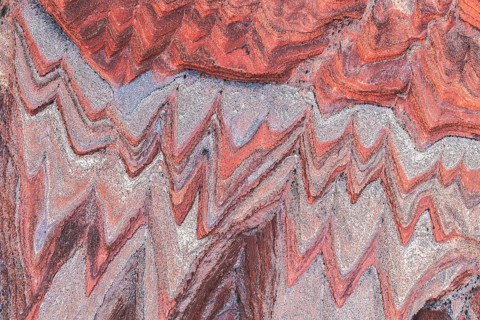 This aerial image captures the intricate, colorful patterns of a rugged canyon landscape near the