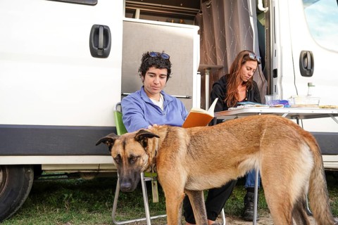 A lesbian couple relaxes outside their motorhome, enjoying a peaceful camping trip with their dog