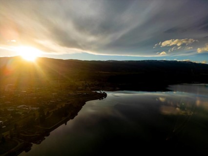 Aerial view of Queenstown in autumn, showcasing a breathtaking sunset over a tranquil lake, with