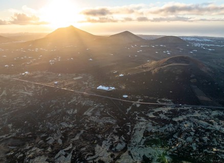 White houses in picturesque volcanic landscape with volcanic craters and lava fields in morning