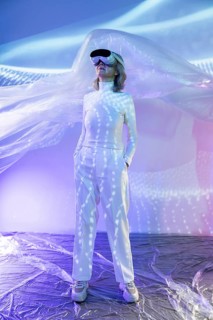 An elderly Asian woman wearing a VR headset explores the immersive world of the metaverse. She