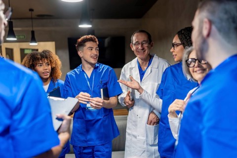 Healthcare team of doctors and nurses collaborating, smiling, and discussing patient care in a