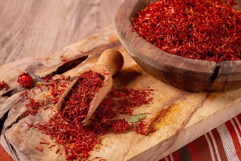 Spice saffron threads, in a wooden bowl, on a wooden table, top view, close-up