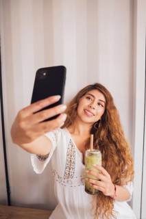 A young American Latin woman enjoys her lifestyle by taking a selfie with her smartphone while