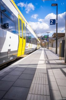 Side view of a yellow and white train next to an empty platform, Hermann Hesse Bahn, ZOB, Calw,