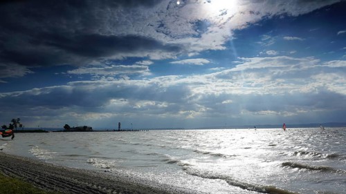 Waves roll across the beach as clouds move across the sunny sky, Lake Neusiedl, Austria