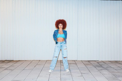 African descendent woman with voluminous afro hair posing confidently in front of a ribbed metal