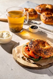 A close-up of a sesame seed bagel with smoked salmon, cream cheese, and capers. Accompanied by a