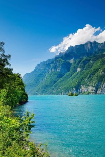 Sunny view over Lake Walen with the small chive island in the turquoise water and mountain range
